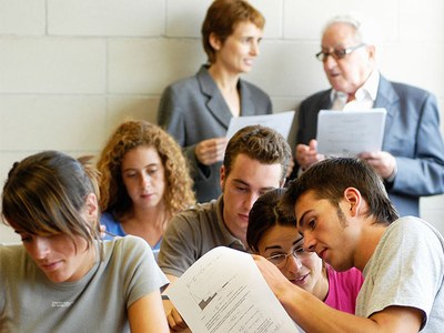 Dos docents en peus, al darrera d'una classe amb estudiantat