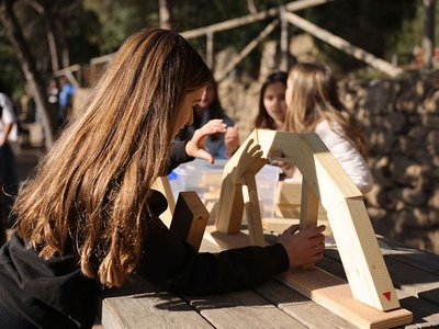 Alumna fent una estructura amb peces de fusta en la activitat d'arquitectura
