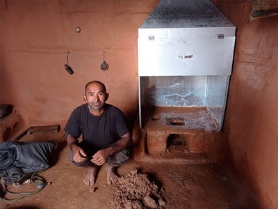 Un habitant d'una zona rural del Nepal al costat d'una cuina-xemeneia, la qual li permetrà viure sense fum
