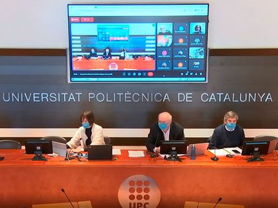 Ana B. Cortinas, secretaria general de la Universitat, Daniel Crespo, rector i Xavier Massó, gerent, asseguts a la Sala de Juntes, durant la sessió, amb la pantalla de les connexions per vídeoconferència al darrere