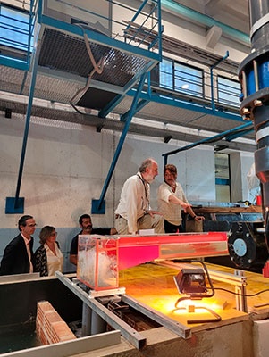 El professor Allen Bateman i la tinenta d'alcaldia Laia Bonet, veient com funciona el model reduït de col·lector al laboratori de la UPC. A l'esquerra, el vicerector Climent Molins; la directora de l'Escola de Camins, Esther Real, i el director d'Ingeniería Gestión y Consultoría Barcelona