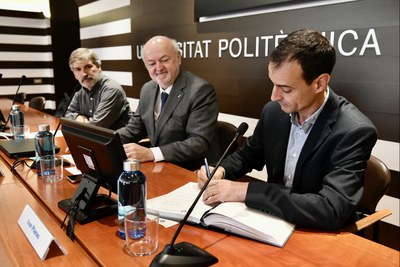 Ivan Planas signant com a nou gerent, acompanyat a al taula pel rector Daniel Crespo i el que ha estat gerent en els darrers cinc anys, Xavier Massó