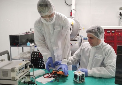 Els doctorands Guillem Gràcia i Solà i Amadeu Gonga i Siles amb la càrrega espacial RITA/3Cat-6, a la sala neta de l'UPC NanoSat Lab