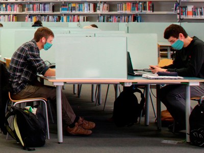 Dos estudiants estudiant cara a cara en una la biblioteca
