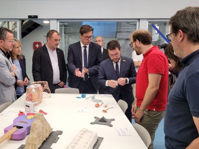 El president de la Generalitat, Pere Aragonès,  mira algunes de les peces fabricades en 3D que li mostren durant la seva visita als laboratoris que conformen la xarxa UPC FAB Terrassa
