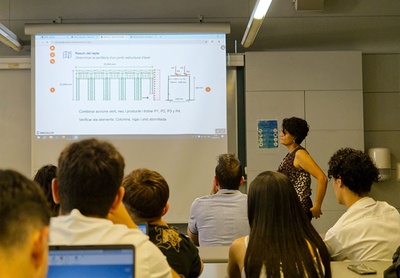 La professora recorda als estudiants quin ha estat el repte plantejat per Mecalux als estudiants de l'assignatura Resistència de Materials 1 de l'EPSEVG.