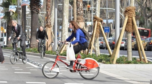 Chica con una bici del Bicing por la calle