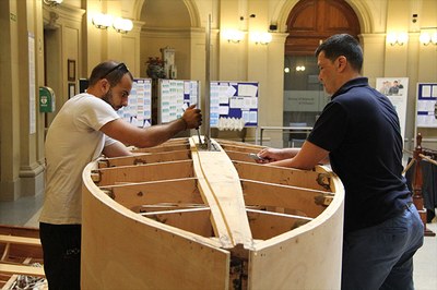 Dos estudiantes de la UPC-FNB botan una embarcación de vela que han construido con planos de hace 100 años