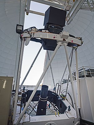 El telescopio William Herschel con el instrumento WEAVE. El posicionador de fibras del WEAVE se encuentra en la caja negra de 1,8 metros situada sobre el anillo superior. Las fibras ópticas recorren la estructura del telescopio hasta la plataforma de la izquierda, que aloja al espectrógrafo. Crédito: Sebastian Kramer.