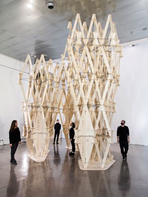 La escultura 'La construcción de valores', diseñada y construida en madera por estudiantes de la ETSAB, da la bienvenida a la exposición. Imagen: Relja Ferusic