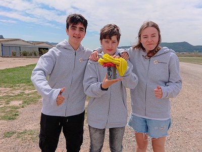 Tres alumnos con un pequeño satélite del tamaño de una lata en la mano